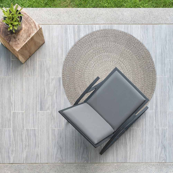 Runder Outdoor-Teppich in Silber, geflochten mit einer größeren und einer kleineren kreisförmigen Fläche. Das Material sieht aus wie Sisal und hat eine textile Struktur.