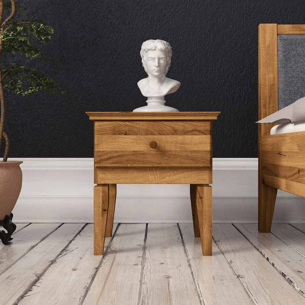 Rustikaler Nachttisch aus Holz steht neben einem Bett. Darauf befindet sich eine weiße Büste, während ein Topf mit einer Pflanze im Hintergrund steht. Die Wand ist dunkel gestrichen.