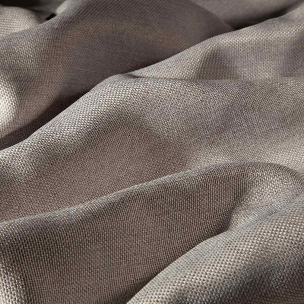 Einfarbiger Dekostoff in Taupe hat eine feine, strukturierte Oberfläche. Der Stoff liegt leicht gewellt und zeigt eine neutrale Farbtonvariante, geeignet für Vorhänge oder andere textile Anwendungen.