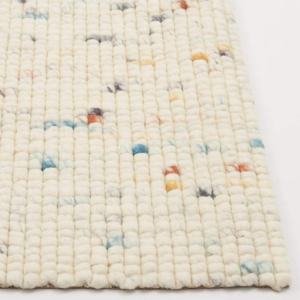 Weißer Webteppich mit bunten, farbigen Punkten in unterschiedlichen Größen. Der Teppich liegt flach auf einem hellen Untergrund und zeigt eine strukturierte Oberfläche aus Schurwolle.