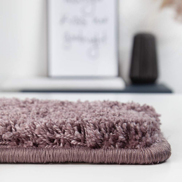 Hochfloriger Teppich in einem sanften Lila-Ton mit weicher Textur. Der Teppich eignet sich für individuelle Raumgestaltungen und vermittelt eine gemütliche Atmosphäre.