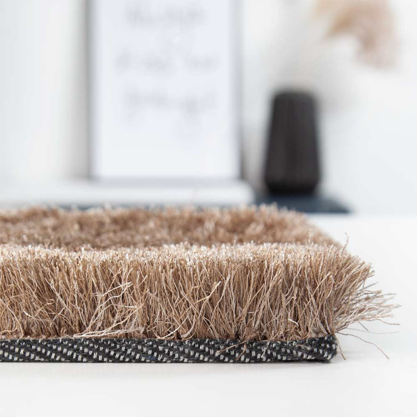 Hochflor-Teppich in brauner Farbe liegt auf einem Boden. Der Teppich zeigt eine weiche, flauschige Textur und hebt sich deutlich vom Untergrund ab. Er ist in einem eleganten Design konzipiert.