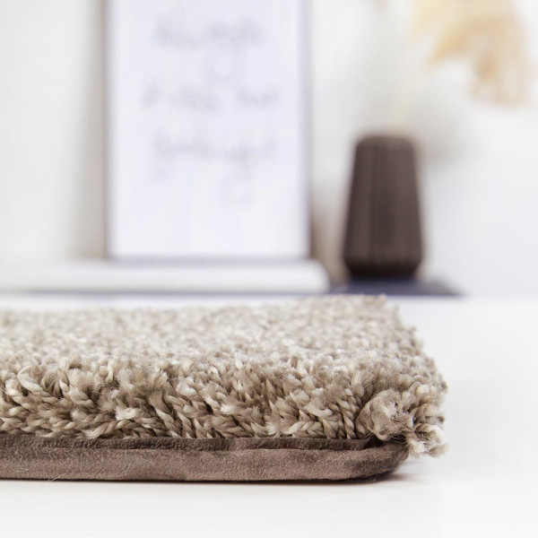Hochflorige, beige Teppichfläche mit einer samtigen, texturierten Oberfläche steht im Fokus. Die Struktur verleiht ein gemütliches Ambiente und ist ideal für individuelle Raumgestaltungen.