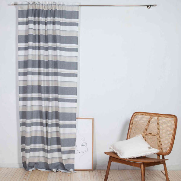 Gestreifter Vorhang in Grautönen hängt an einer silbernen Stange. Der Stoff ist leicht und plisseeartig drapiert, was eine luftige Atmosphäre schafft.