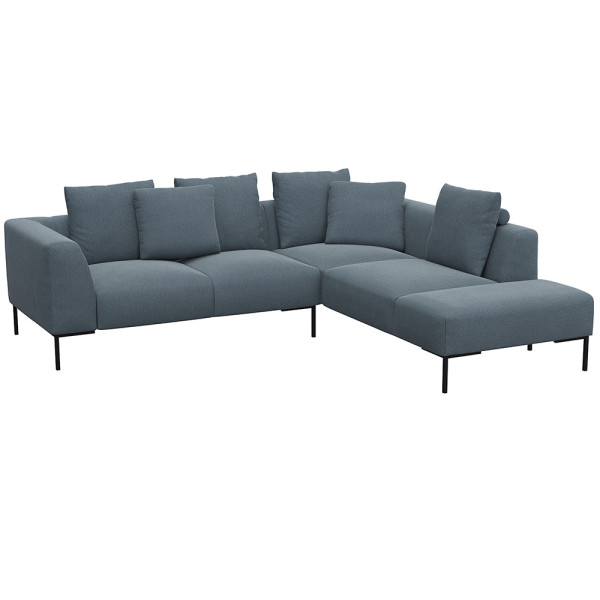 Helles, modernes Ecksofa SAVA mit offenem Ende. Das Sofa besitzt mehrere bequeme Kissen und steht auf schwarzen Metallbeinen. Es eignet sich ideal für stilvolle Wohnräume.