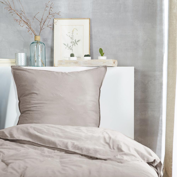 Flanell-Bettwäsche in sanfter, beiger Farbe liegt drapiert auf einem Bett. Ein Kissenbezug und die Bettdecke sind sichtbar, zusammen mit einem Detailansicht-Ausschnitt der Naht.