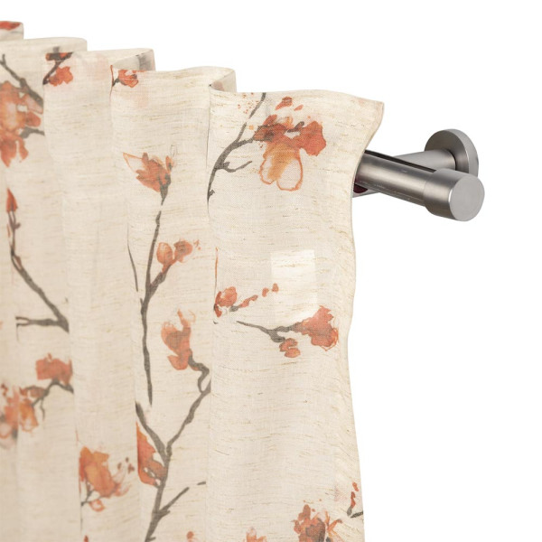 Fertigschal Kianna mit blumigem Design in Orange und Beige hängt an einer silbernen Gardinenstange. Der Stoff ist halbtransparent und verleiht dem Raum eine helle Atmosphäre.