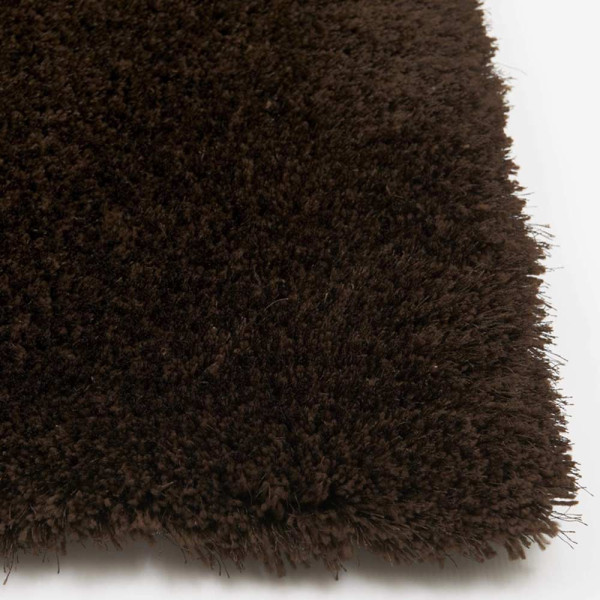 Dunkelbrauner, hochfloriger Teppich liegt flach auf dem Boden. Die weichen Fasern sind dicht und wirken einladend, ideal für gemütliche Räume.