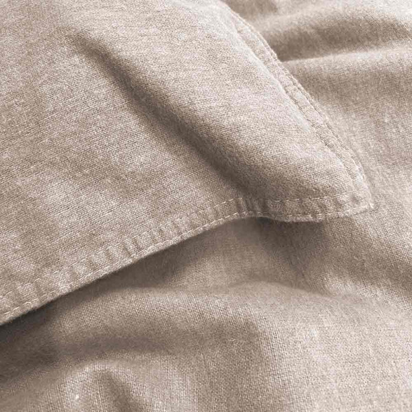 Flanell-Bettwäsche in sanfter, beiger Farbe liegt drapiert auf einem Bett. Ein Kissenbezug und die Bettdecke sind sichtbar, zusammen mit einem Detailansicht-Ausschnitt der Naht.