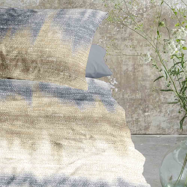Flanell-Bettwäsche mit einem farbigen Muster in Blau- und Erdtönen liegt glatt auf einer Fläche. Dazu gehören zwei passende Kissenbezüge im gleichen Design.