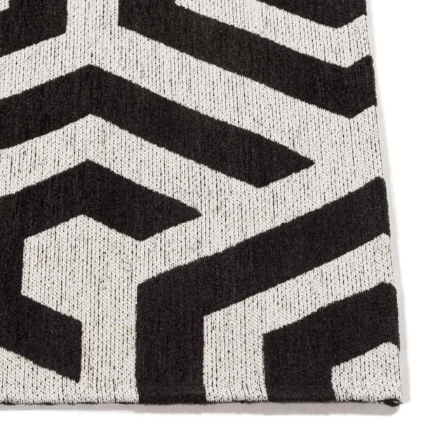 Geometrisch gestalteter Teppich mit schwarz-weißen hexagonalen Mustern liegt flach auf einer Oberfläche. Der Teppich eignet sich für stilvolle Innenräume.