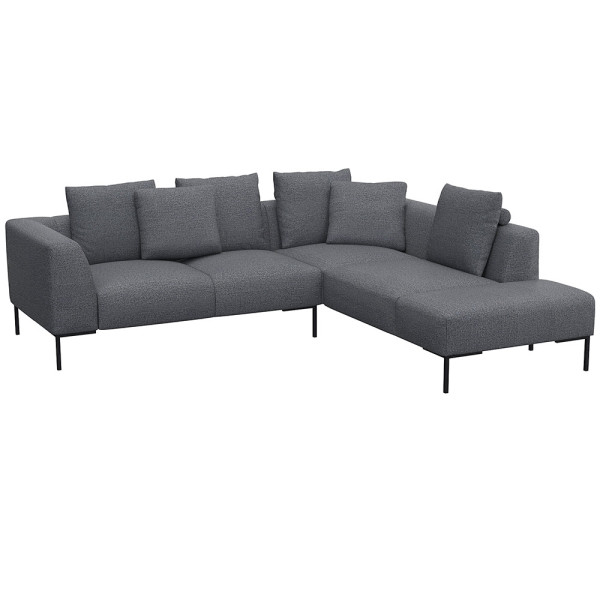 Helles, modernes Ecksofa SAVA mit offenem Ende. Das Sofa besitzt mehrere bequeme Kissen und steht auf schwarzen Metallbeinen. Es eignet sich ideal für stilvolle Wohnräume.