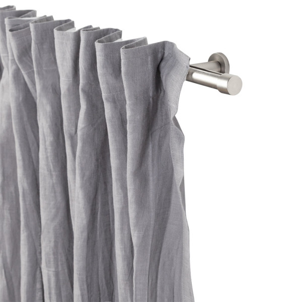 Grau gefalteter Vorhang aus Baumwolle und Leinen hängt an einer silbernen Stange. Der Vorhang ist halbtransparent und hat eine natürliche Textur.