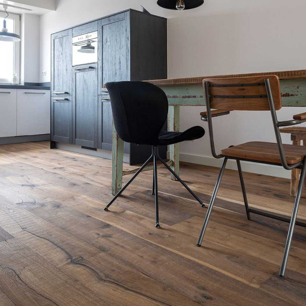 Dunkles Parkett aus Eiche, mit einer strukturierten Oberfläche, liegt verlegt auf dem Boden. Es zeigt verschiedene Farbtöne und Maserungen, die dem Holz einen rustikalen Charakter verleihen.