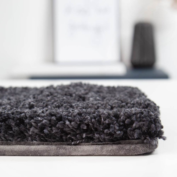 Dunkler Hochflorteppich in Struktur mit weichem, flauschigem Material. Der Teppich eignet sich für individuelle Anpassungen nach Maß, um verschiedenen Gestaltungsvorstellungen gerecht zu werden.