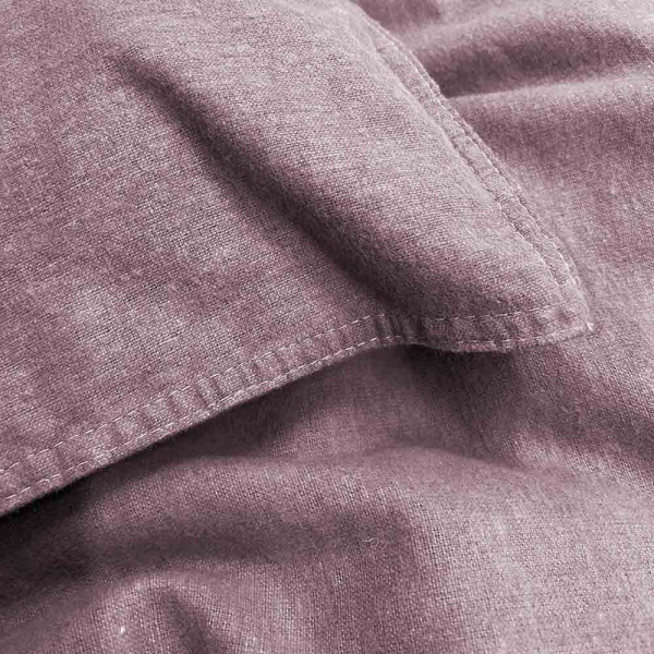 Flanell-Bettwäsche in der Farbe Mauve, bestehend aus einem Kopfkissenbezug und einem Bettdeckenbezug, liegt ordentlich auf einem Untergrund mit einer hervorgehobenen Nahtdetailansicht.