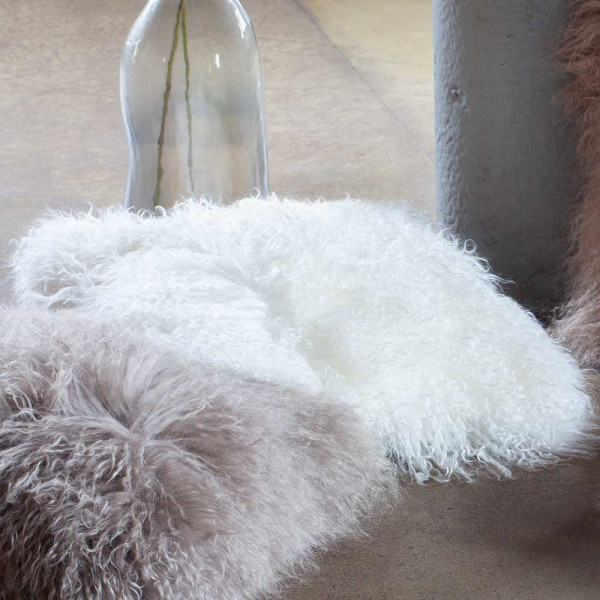 Flauschige Kissenhülle aus Echtfell in Weiß. Die Kissenhülle hat eine quadratische Form und ist weich sowie einladend für gemütliche Wohnräume.