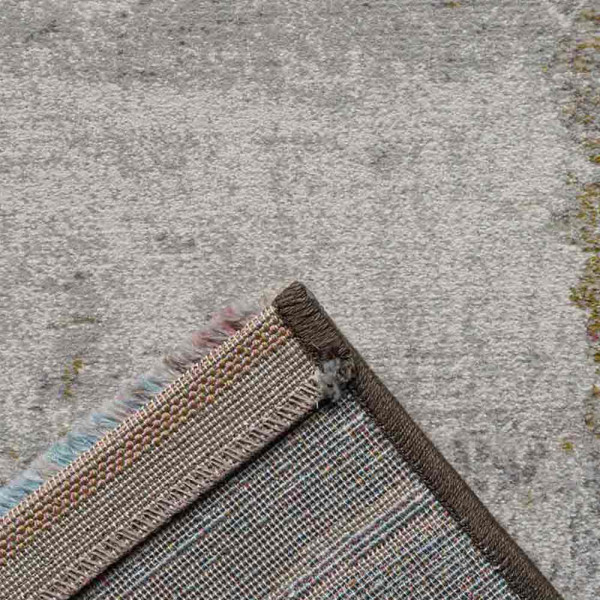 Grauer Kurzflor-Teppich Argentum 63723 mit abstraktem Muster in verschiedenen Grautönen und leicht goldfarbenen Akzenten liegt auf einem hellen Untergrund. Er vermittelt ein modernes Ambiente.