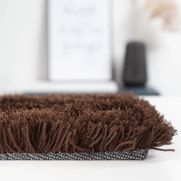Dunkelbrauner, hochfloriger Teppich liegt flach auf dem Boden. Die weichen Fasern sind dicht und wirken einladend, ideal für gemütliche Räume.