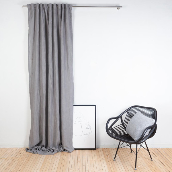 Grau gefalteter Vorhang aus Baumwolle und Leinen hängt an einer silbernen Stange. Der Vorhang ist halbtransparent und hat eine natürliche Textur.