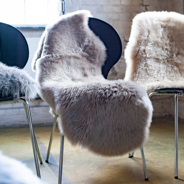 Doppeltes Lammfell in der Farbe Natur liegt flach auf einer Oberfläche. Die Oberfläche ist weich und pelzig, mit einer länglichen Form von 50 x 160 cm.