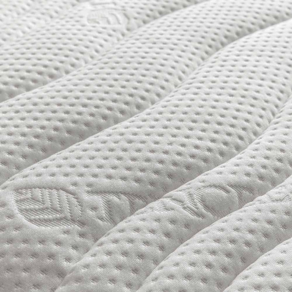 Elektrisch verstellbares Boxspringbett in Grau mit einem grauen Kopfteil und hellen Kissen. Eine Decke und ein Dekokissen liegen auf der Matratze. Ein Holzofenfenster zeigt eine LED-Lichtstimmung an.