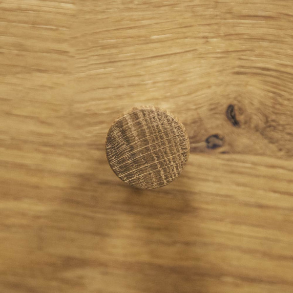 Rustikaler Nachttisch aus Holz steht neben einem Bett. Darauf befindet sich eine weiße Büste, während ein Topf mit einer Pflanze im Hintergrund steht. Die Wand ist dunkel gestrichen.