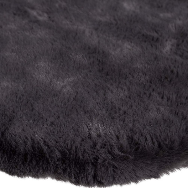 Kuscheliger, steinfarbiger Fellteppich Arvid Deluxe mit geschwungener Form liegt auf einem hellen Untergrund. Der Teppich ist weich und eignet sich für komfortables und stylisches Wohnen.