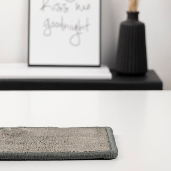 Dunkler, kurzfloriger Teppich im Crushed Velvet-Stil mit einer unregelmäßigen Struktur. Der Teppich steht im Fokus der Präsentation als modisches Einrichtungselement.