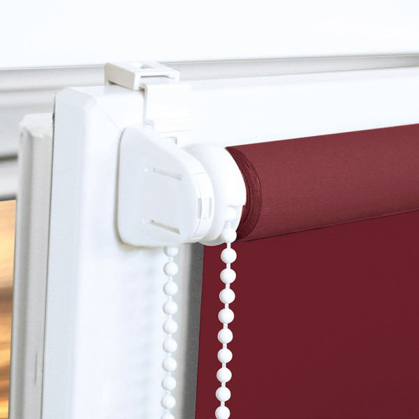 Rotes EasyFix Seitenzugrollo Alicia mit Zugkette hängt am Fenster. Eine Stehlampe steht neben einem beigen Sessel, und ein Blumentopf ziert den Tisch.