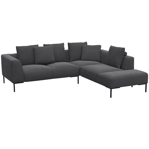 Helles, modernes Ecksofa SAVA mit offenem Ende. Das Sofa besitzt mehrere bequeme Kissen und steht auf schwarzen Metallbeinen. Es eignet sich ideal für stilvolle Wohnräume.