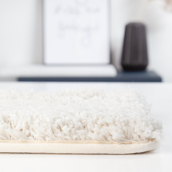 Weißer, hochfloriger Teppich mit samtiger Oberfläche liegt flach auf dem Boden. Die Struktur zeigt weiche, dichte Fasern. Der Teppich eignet sich für individuelle Maßanfertigung und ist in verschiedenen Farben erhältlich.