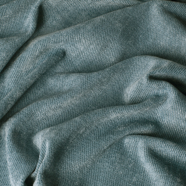 Weicher, blauer Dekostoff liegt in Falten. Die strukturierte Oberfläche zeigt ein geometrisches Muster, das gleichmäßig verläuft. Dieser Stoff eignet sich für Vorhänge oder andere Dekorationszwecke.