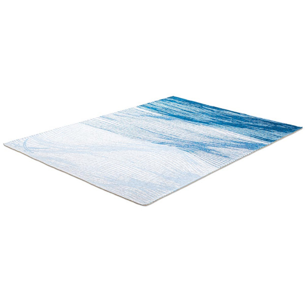 Weiß-blauer Teppich mit wellenförmigem Muster in verschiedenen Blautönen. Der Teppich hat eine flachgewebe Struktur und ist für den Innenbereich geeignet.