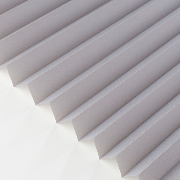 Hellgraue Plissee-Jalousien mit gefalteter Struktur sind ordentlich in Reihen angeordnet. Sie bieten Sichtschutz und sind maßgefertigt für Fenster.