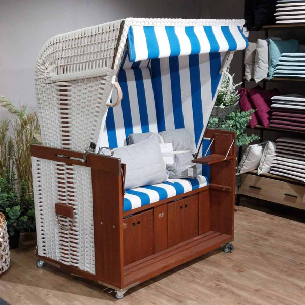 Profi Strandkorb aus Holz mit blau-weiß gestreiften Polstern, zwei Sitzplätzen und ausklappbaren Fußteilen. Der Korb hat ein abnehmbares Dach und ist ideal für den Einsatz am Strand.