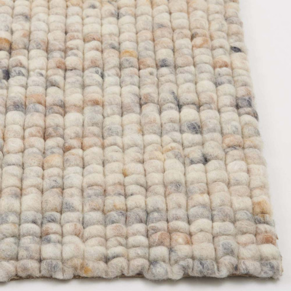 Zarter Webteppich in Beige, bestehend aus Schurwolle. Die strukturierte Oberfläche zeigt kleine, runde Muster und verleiht dem Raum eine gemütliche Atmosphäre. Ideal für nachhaltige Einrichtungsstile.