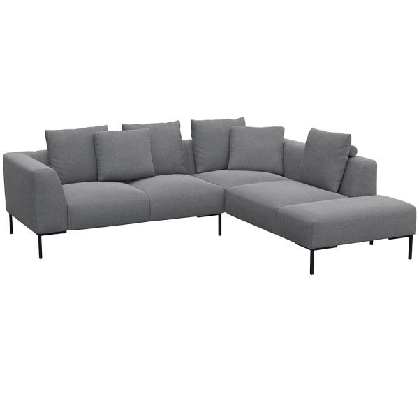 Helles, modernes Ecksofa SAVA mit offenem Ende. Das Sofa besitzt mehrere bequeme Kissen und steht auf schwarzen Metallbeinen. Es eignet sich ideal für stilvolle Wohnräume.