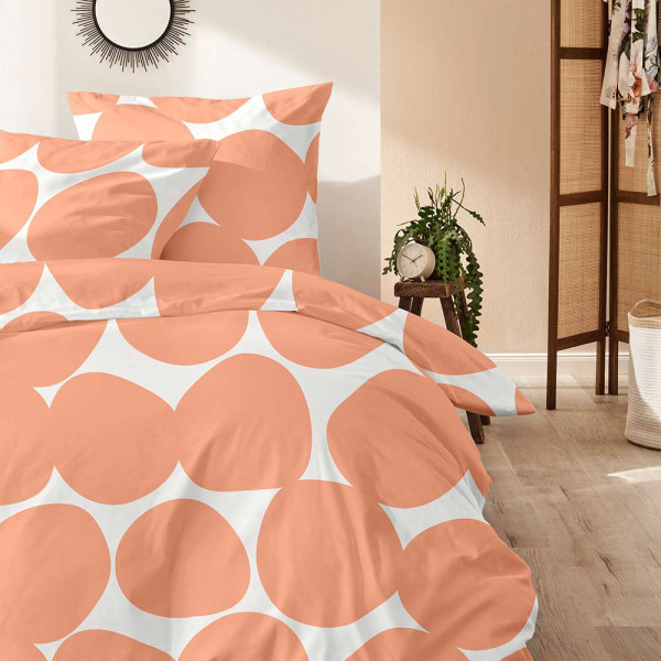 Bettwäsche mit apricot-weißer Punktmusterung liegt ordentlich gefaltet auf einer Fläche. Die Decke und das Kissen haben ein harmonisches Design.