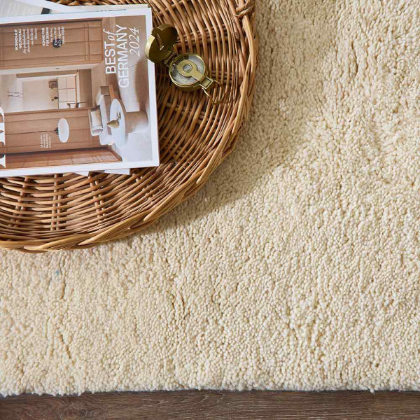 Beiger, flacher Teppich im minimalistischen Design, liegt auf einem neutralen Untergrund. Er präsentiert sich in einem klaren, einheitlichen Farbton ohne Muster oder Verzierungen.