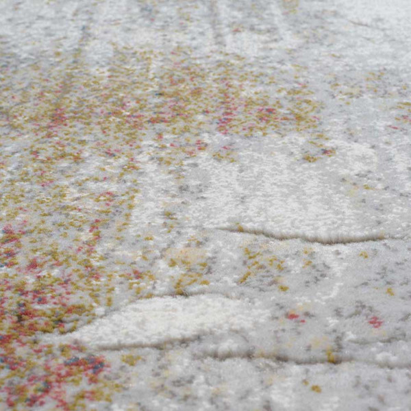 Grauer Kurzflor-Teppich Argentum 63723 mit abstraktem Muster in verschiedenen Grautönen und leicht goldfarbenen Akzenten liegt auf einem hellen Untergrund. Er vermittelt ein modernes Ambiente.