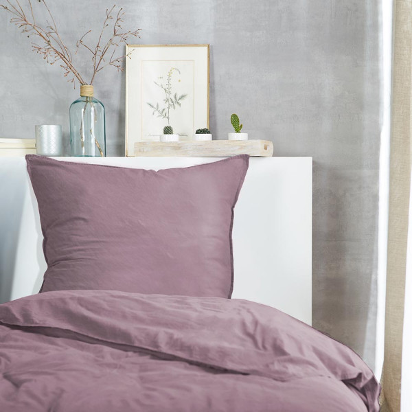 Flanell-Bettwäsche in der Farbe Mauve, bestehend aus einem Kopfkissenbezug und einem Bettdeckenbezug, liegt ordentlich auf einem Untergrund mit einer hervorgehobenen Nahtdetailansicht.