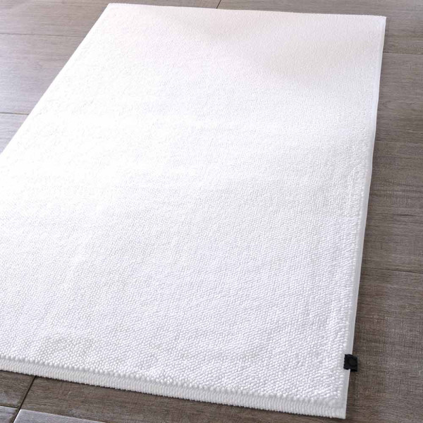 Weißer Badteppich 1007 von Cawö liegt flach auf dem Boden. Er hat eine rechtwinklige Form und eine weiche Textur. Die Maße sind 60 x 100 cm.