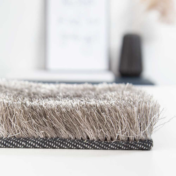 Hochflorteppich in einem sanften Braun-Ton mit flauschiger Oberfläche liegt flach ausgebreitet. Der Teppich ist aus hochwertigem Polyester gefertigt und eignet sich für individuelle Maßanfertigung.