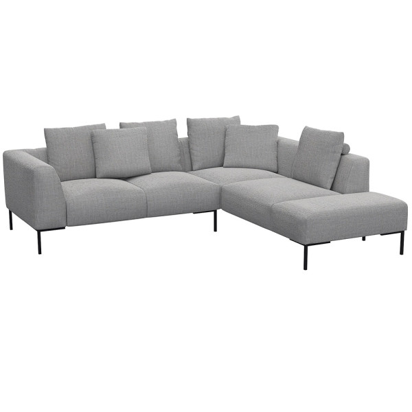 Helles, modernes Ecksofa SAVA mit offenem Ende. Das Sofa besitzt mehrere bequeme Kissen und steht auf schwarzen Metallbeinen. Es eignet sich ideal für stilvolle Wohnräume.