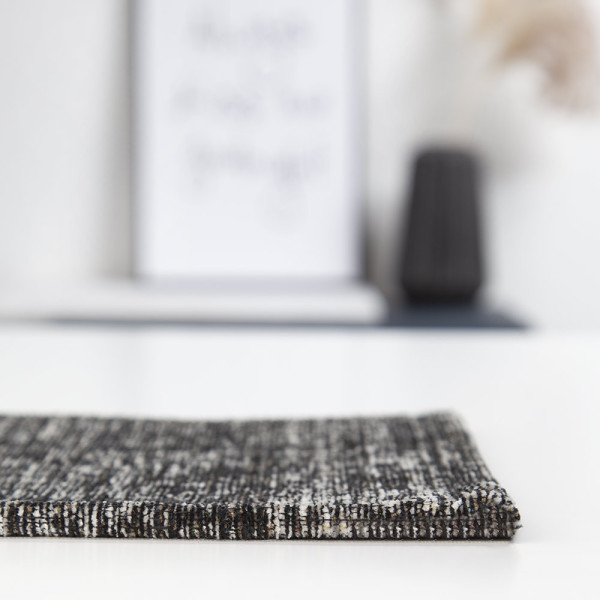 Dunkler Webteppich mit strukturiertem Muster und subtilen Farbnuancen. Der Teppich ist strapazierfähig und eignet sich für vielfältige Wohnanwendungen.