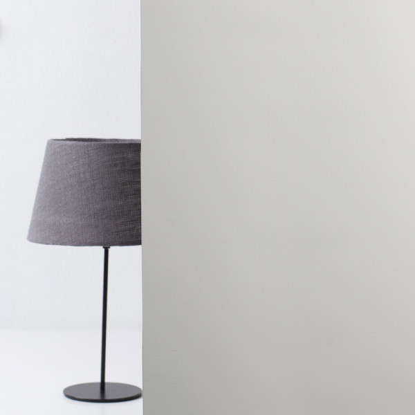 Grau gestrichene Textiloberfläche eines Rollos. Das Material wirkt strukturiert und lässt sich für individuelle Lichtregulierung verwenden. Das Rollo ist für Maßanfertigungen geeignet.