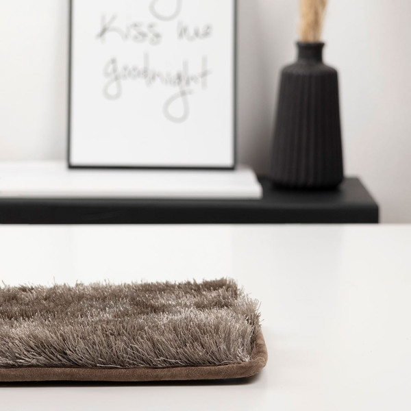 Dunkler, weicher Webteppich aus Polyester zeigt eine strukturierte Oberfläche mit langen Fasern. Die Farbe reicht von Braun bis Taupe und vermittelt ein luxuriöses Ambiente.