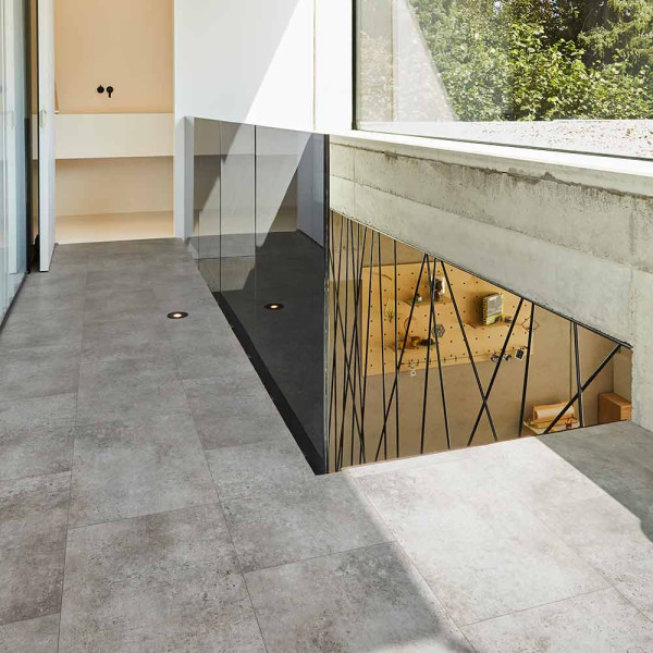 Graue, strukturierte Textur eines Vinylbodens mit einem Mischung aus glatten und rauen Oberflächen zeigt verschiedene Farbtöne von Grau. Diese Oberfläche eignet sich für moderne Innenraumgestaltungen.