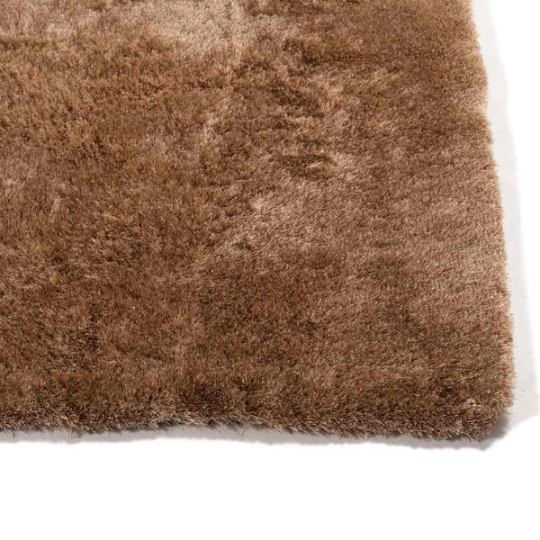 Hochflor-Teppich in brauner Farbe liegt auf einem Boden. Der Teppich zeigt eine weiche, flauschige Textur und hebt sich deutlich vom Untergrund ab. Er ist in einem eleganten Design konzipiert.